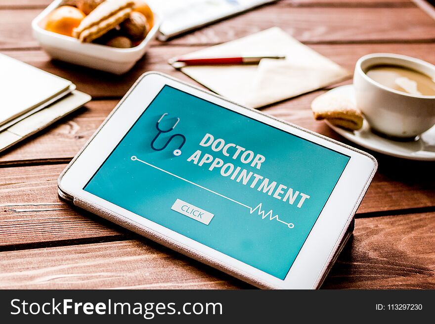 Concept of appointment to doctor online on wooden background