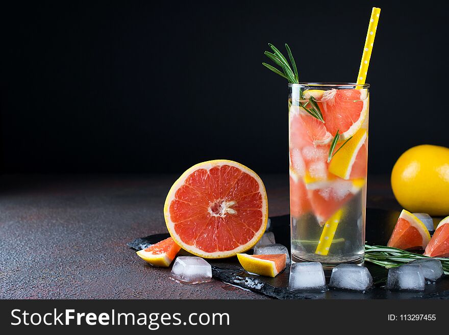 Grapefruit lemonade. Two glasses of refreshing drink, water with grapefruit, rosemary branches and ice.