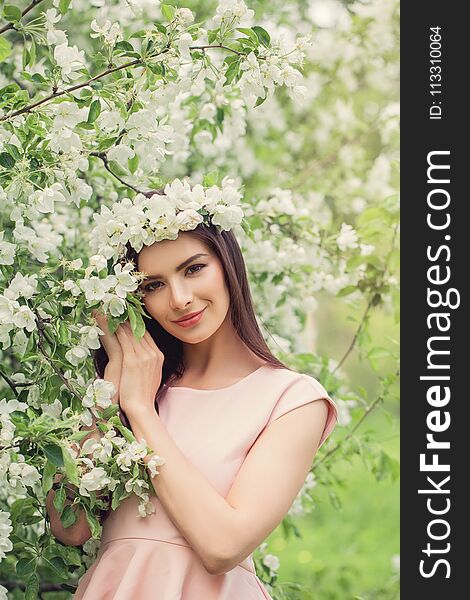 Spring woman outdoors on flowers background. Pretty young female model resting in blossom spring flowers garden