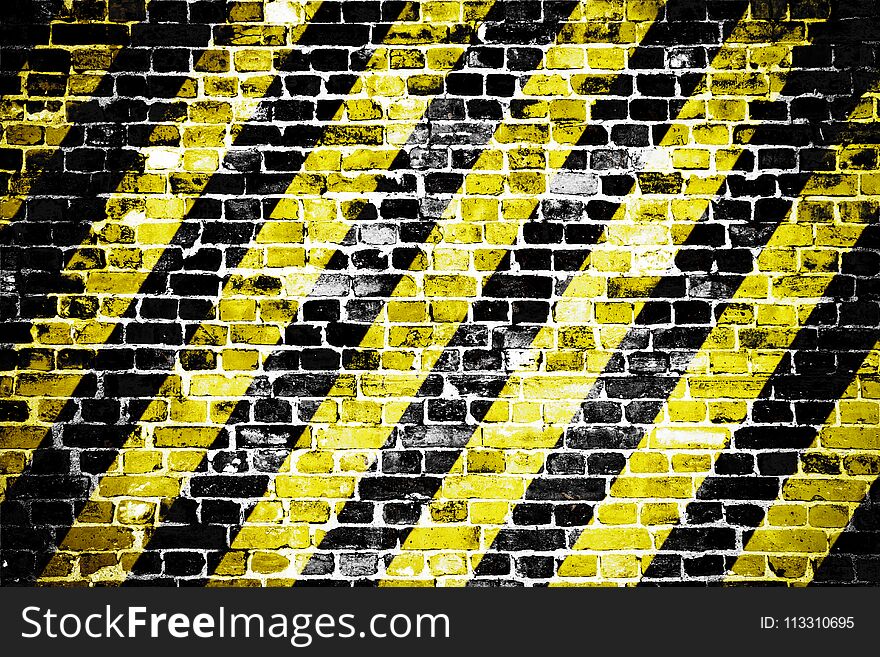 Old and weathered grungy brick wall with danger or attention black and yellow diagonal stripes as texture background.