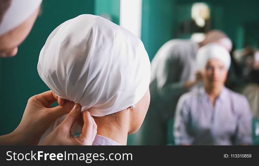 Two muslim women to tie Islamic turban, preparing for a wedding near mirror