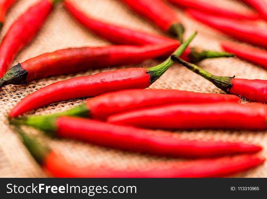 Close up of red hot chilli peppers scattered on beige canvas fabric. Selective focus. Close up of red hot chilli peppers scattered on beige canvas fabric. Selective focus