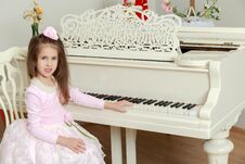 Little Girl At A White Grand Piano. Stock Photos