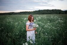 Beautiful Brunette In The Evening Summer Field With Bouquet Of Meadow Flowers Royalty Free Stock Photo