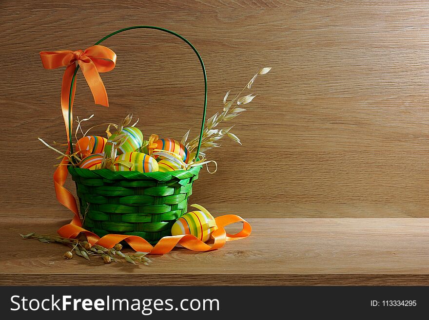 Green basket with painted eggs on a wooden background. Green basket with painted eggs on a wooden background.