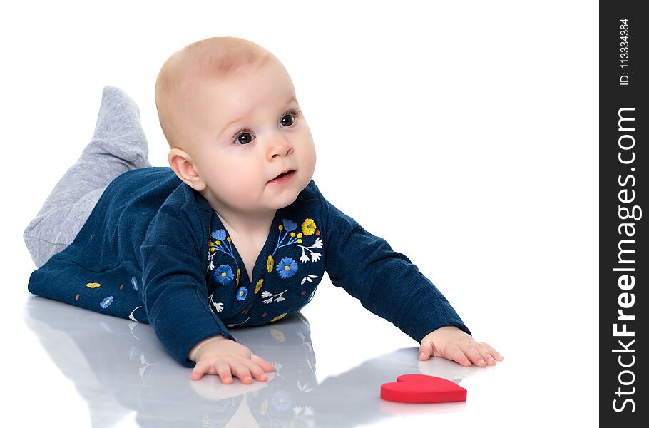 A cute, very little girl is lying on the floor on a white backgr