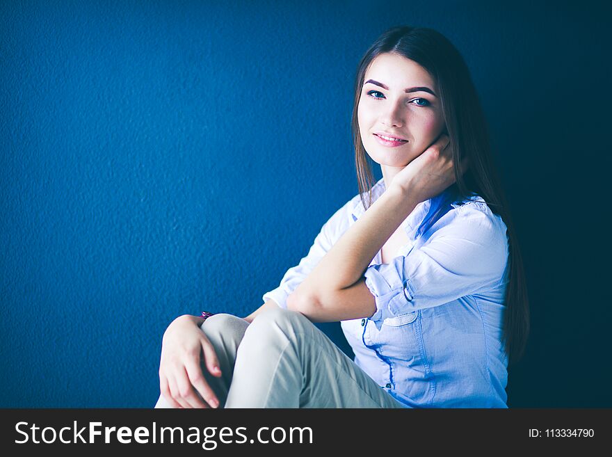 Young Woman Sitting On The Floor Near Dark Wall