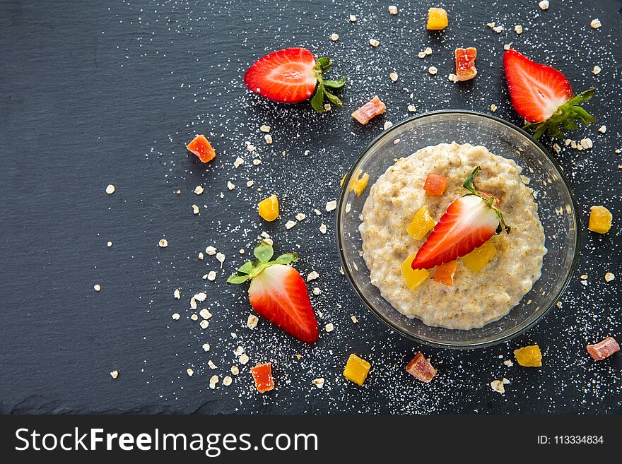 Oatmeal for Breakfast with strawberries and dried fruits still Life on black background. Oatmeal for Breakfast with strawberries and dried fruits still Life on black background