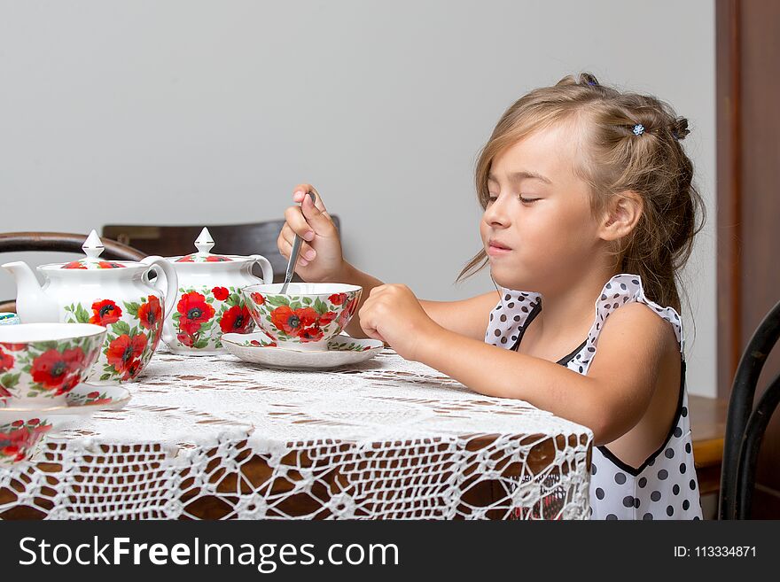 A little girl is drinking tea at the table. Stylized as a room of the fifties of last century. Retro style.