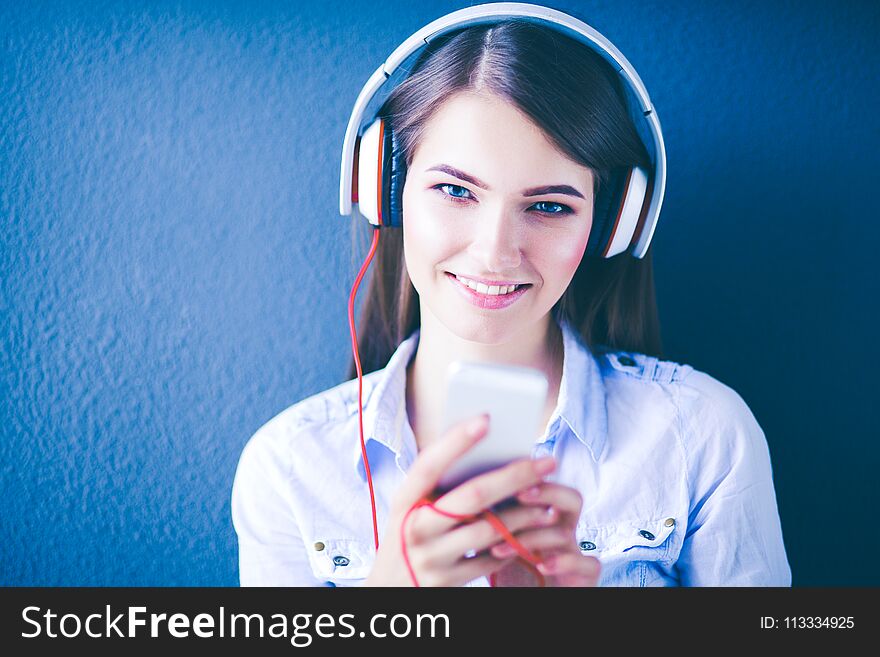 Young happy girl sitting on floor and listening music