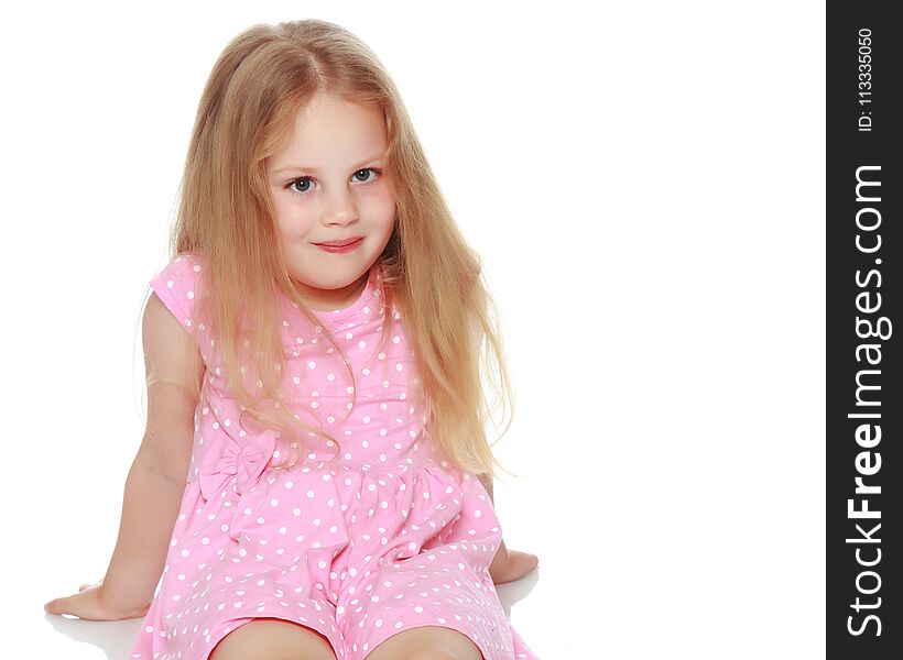 Little girl is sitting on the floor. The concept of a happy childhood. Isolated on white background.