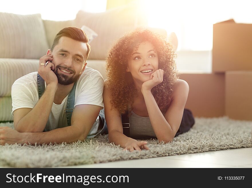 Young Couple Lying On The Rug On The Background Of A New Apartme