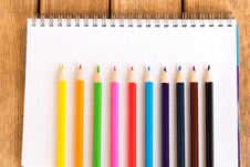 Set Of Colored Pencils On School Notebook On Wooden Background . Stock Photos