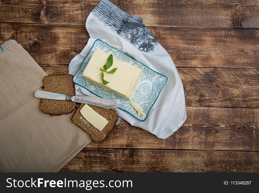 A piece of bread with butter on wooden background and napkin