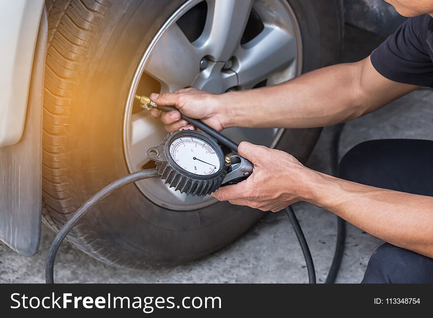 Close up mechanic inflating tire and checking air pressure with gauge pressure in service station