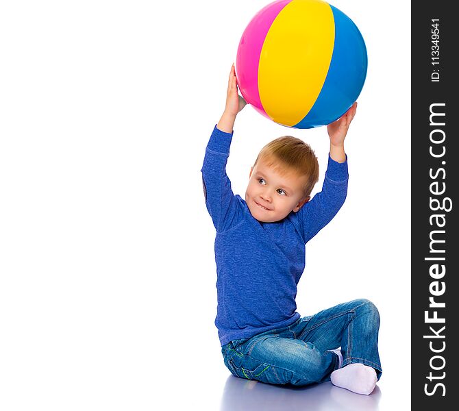 A cheerful little boy is playing with a ball in the studio on a white background. The concept of a happy childhood, game and sport. Isolated. A cheerful little boy is playing with a ball in the studio on a white background. The concept of a happy childhood, game and sport. Isolated.