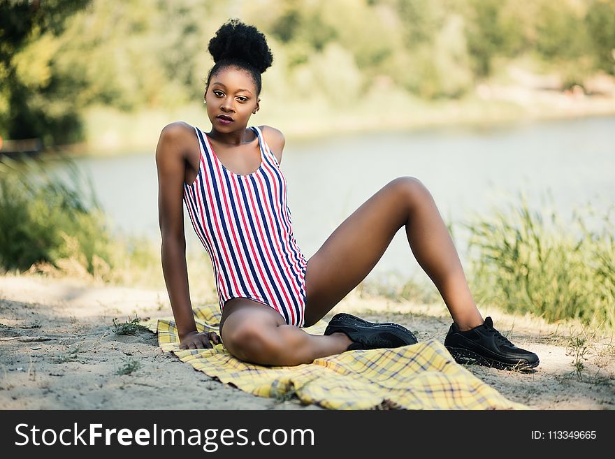 Woman In White, Red, And Blue Striped One-piece Suit Sitting Near River