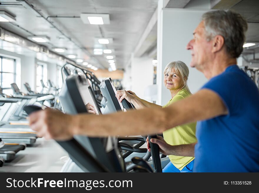 Happy senior woman training on stair stepper at gym