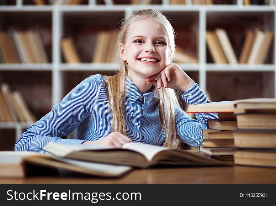 Teenage girl reading a book in library. Teenage girl reading a book in library