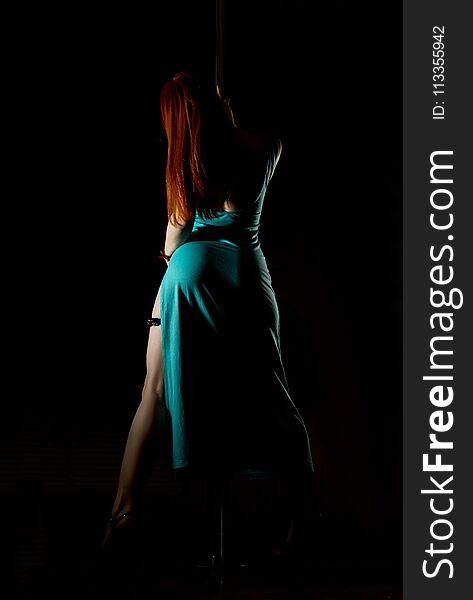 Woman Pole Dancer In A Long Turquoise Dress With A Slit On A Dark Background