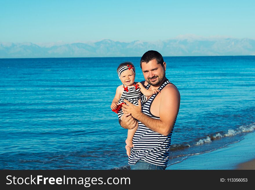 Happy father playing with cute little daughter at the beach