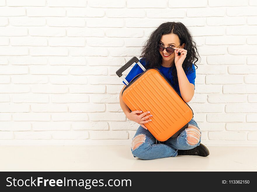 Happy young woman in sunglasses holds modern suitcase on white b