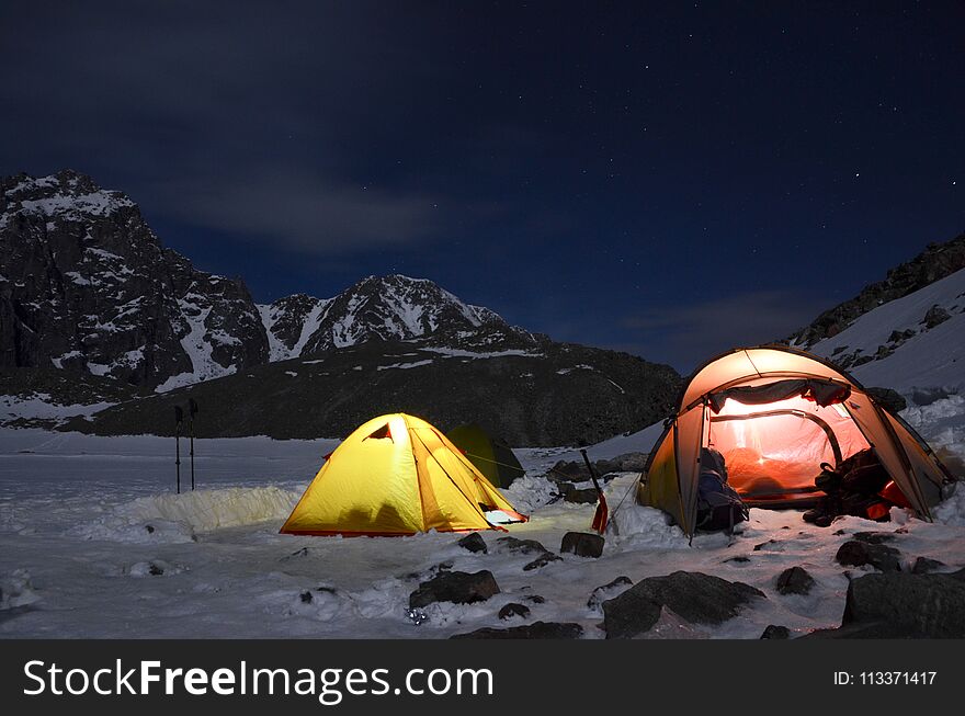 Magnificent view of the snow-capped mountains in a moonlit night. Night view of Mount Munku-Sardyk. Munku-Sardyk in the light of the moon. Tent and Camping hill landscape of at night.