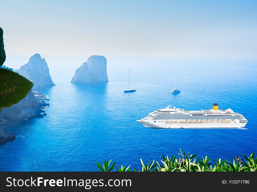 Famous Faraglioni cliffs and Tyrrhenian Sea blue water with criuse ship, Capri island, Italy