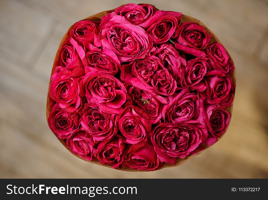 Beautiful bouquet of an adorable crimson peony roses wrapped in craft paper on a blurred background. Beautiful bouquet of an adorable crimson peony roses wrapped in craft paper on a blurred background