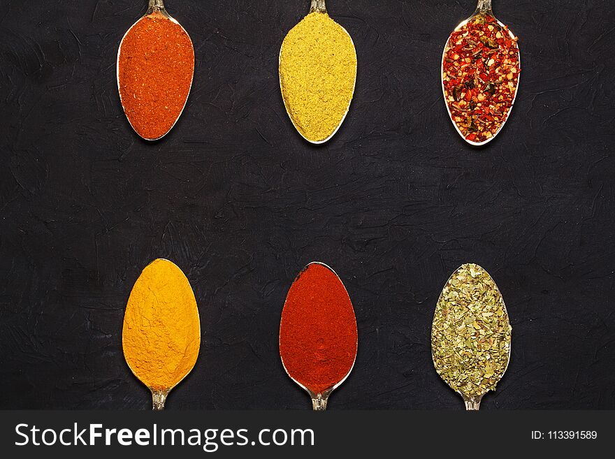 Spices In Silver Spoons, Turmeric, Paprika, Cardamom, Basil. On A Wooden Table. View From Above.