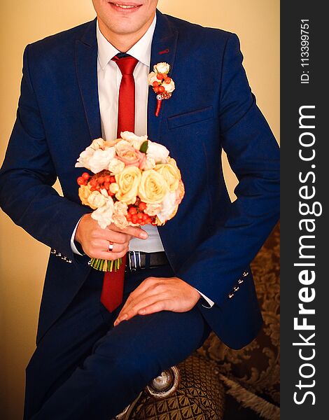 Groom holding a beautiful bouquet of tender and colorful flowers tied with a pretty ribbon. Groom holding a beautiful bouquet of tender and colorful flowers tied with a pretty ribbon