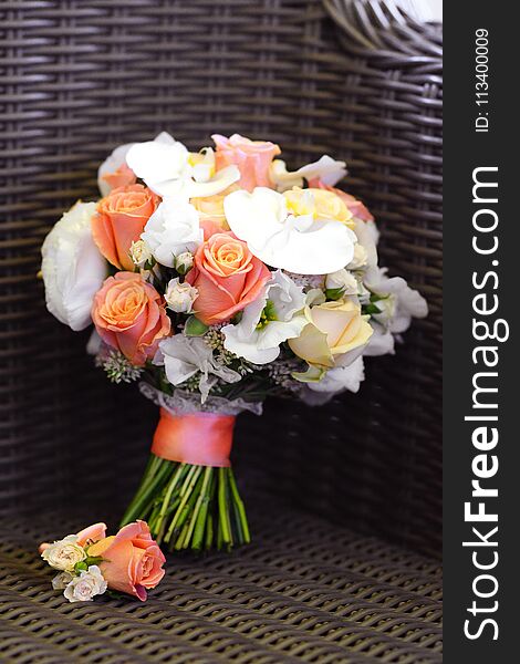 Wedding bouquet lies on a beige chair. The bouquet consists of wild flowers and cream-colored roses. It is tied up with a white cloth. It is lighten with natural light. Wedding bouquet lies on a beige chair. The bouquet consists of wild flowers and cream-colored roses. It is tied up with a white cloth. It is lighten with natural light.