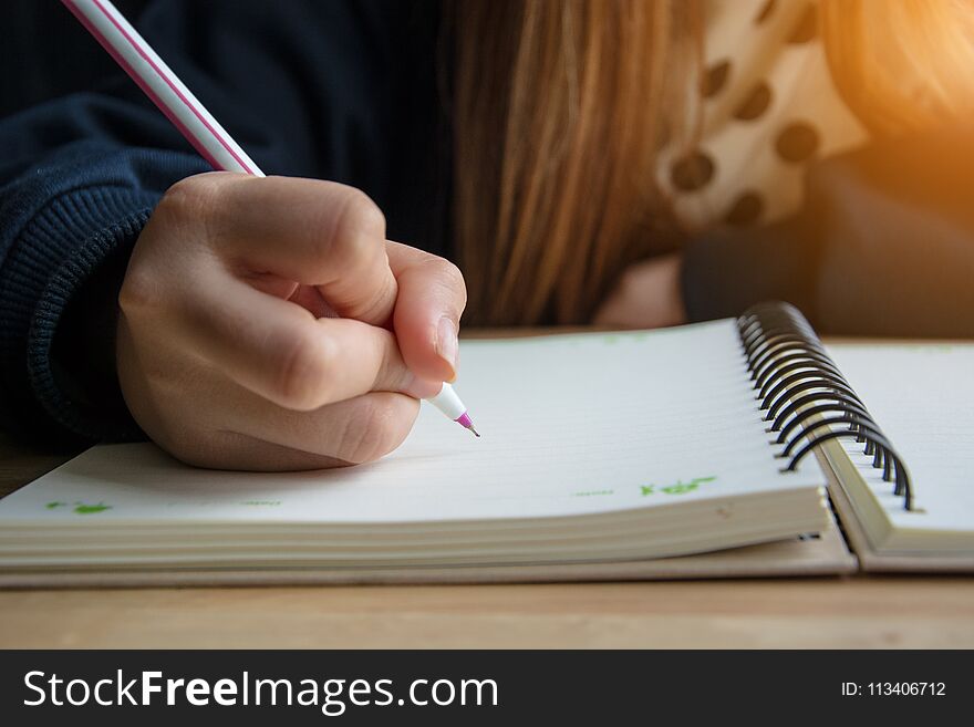 Female hand writing in notebook on the table.