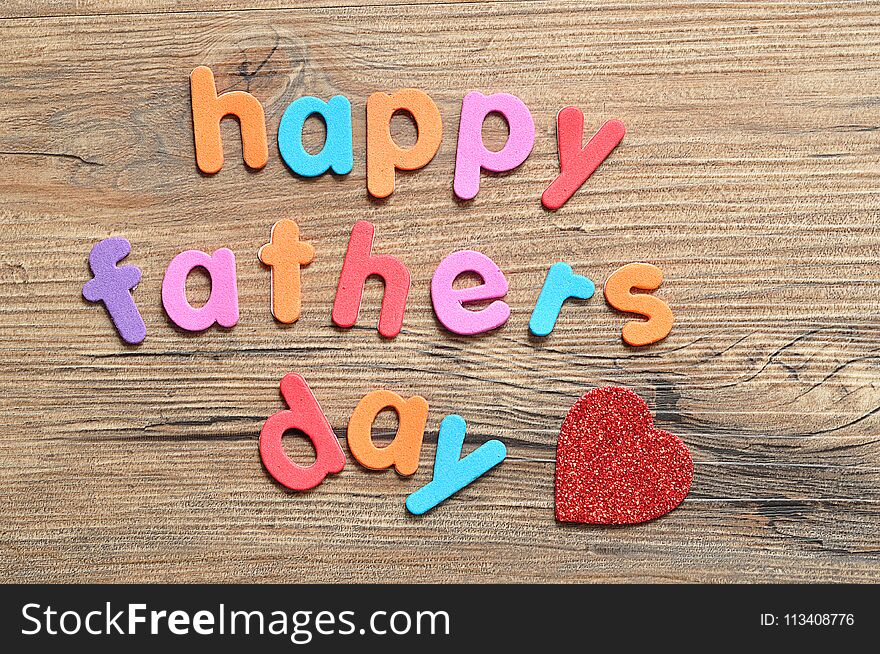 Happy fathers day on a wooden background with a red heart. Happy fathers day on a wooden background with a red heart