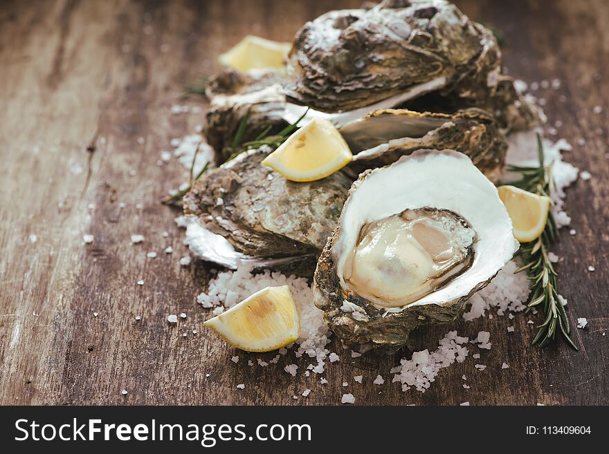 A photo of freshly opened oysters on a wooden background texture with copyspace