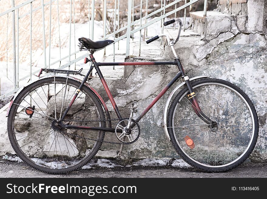 The old bicycle stands near the building