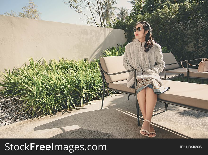 Woman Wearing Hoodie Sitting on Lounge Chair