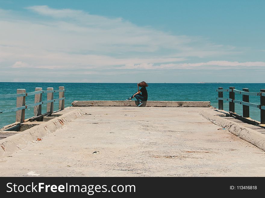 Person Sitting on the Edge of the Beach Dock