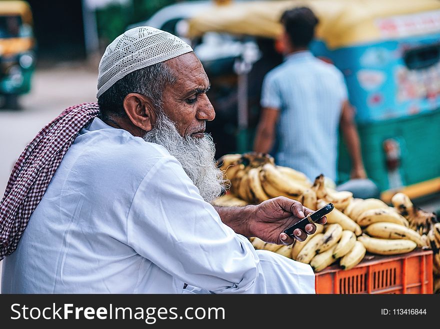 Man In White Thobe Coat Holding Mobile Phone