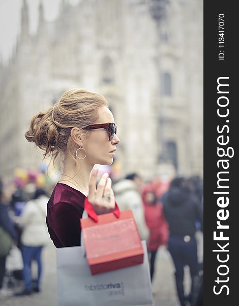 Woman Wearing Red Top Carrying Red Paper Tote Bag