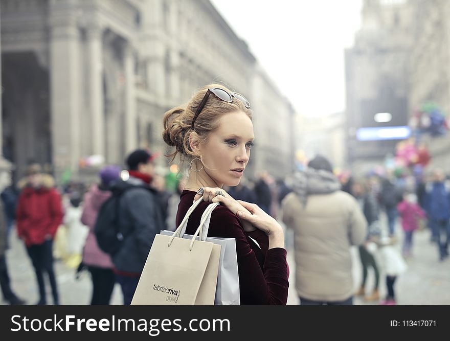 Woman Wearing Maroon Long-sleeved Top Carrying Brown And White Paper Bags In Selective Focus Photography