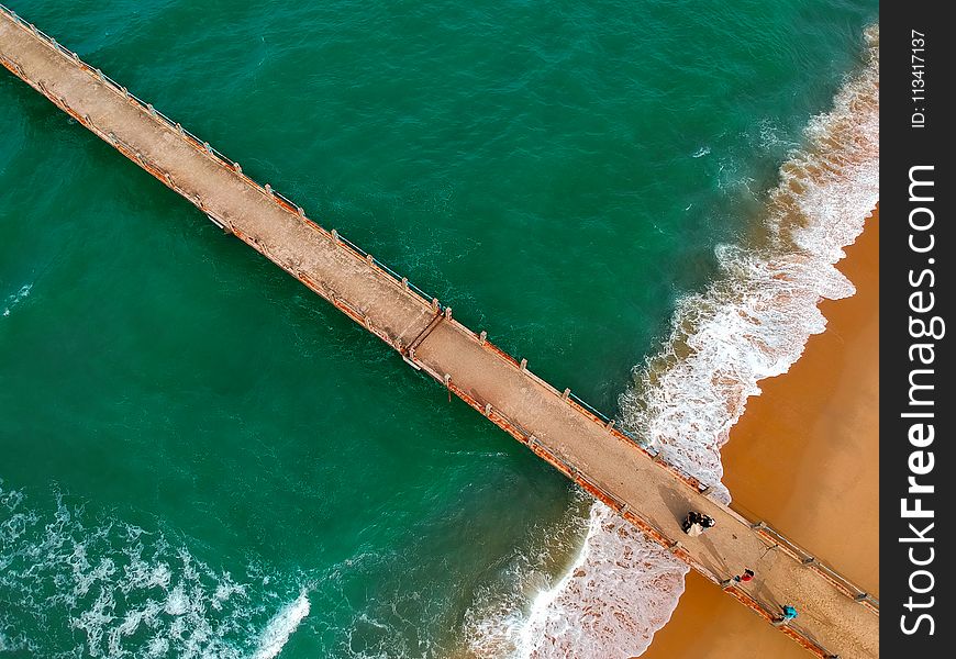 Aerial Photography of Brown Boardwalk Near Green Water on Beach