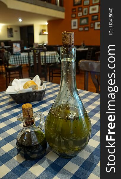 A italian restaurant traditional scene with some old glass bottles in the middle of the table containing oil to be added to the food, bread basket in the back. A italian restaurant traditional scene with some old glass bottles in the middle of the table containing oil to be added to the food, bread basket in the back