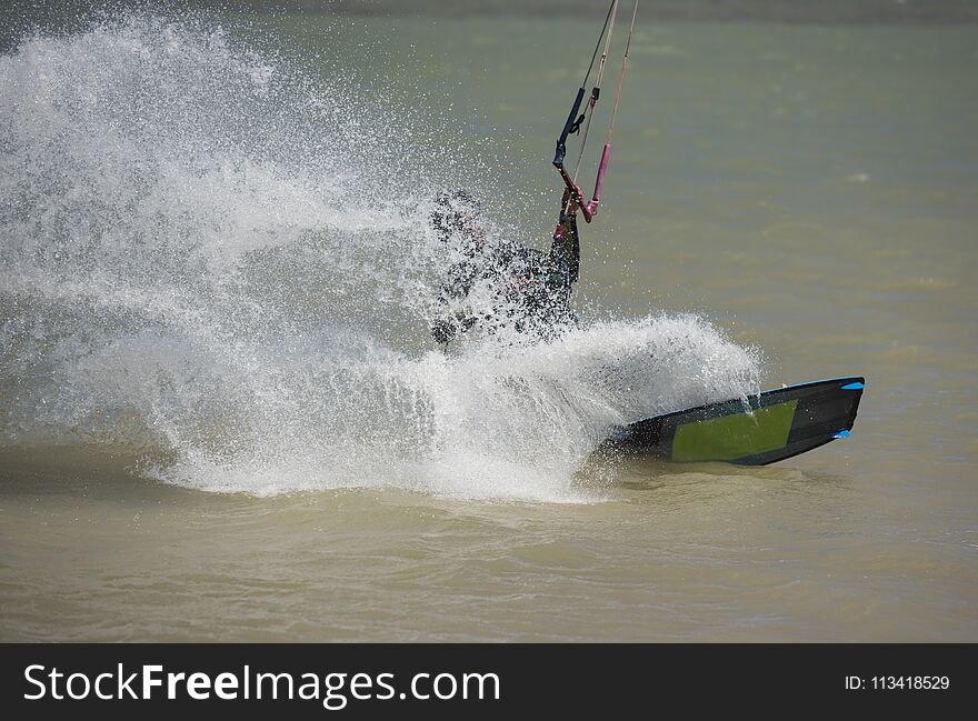 Recreational sport kitesurfer surfing over lagoon in tropcial sea with wake splash. Recreational sport kitesurfer surfing over lagoon in tropcial sea with wake splash