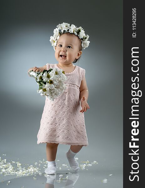 Beautiful little baby girl, with bouquet and diadem of flowers