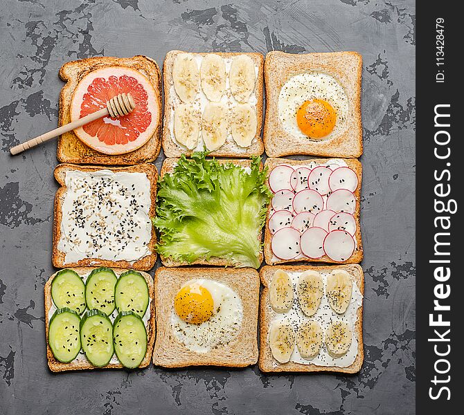 Different toasts on a gray background. Toast with egg, banana, salad, cream cheese, cucumber, radish, grapefruit and honey.