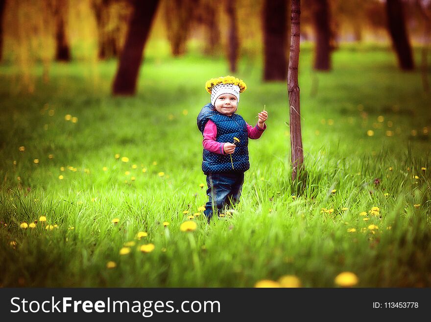 Adorable young little girl with wreath on head standing on green lawn. Adorable young little girl with wreath on head standing on green lawn.