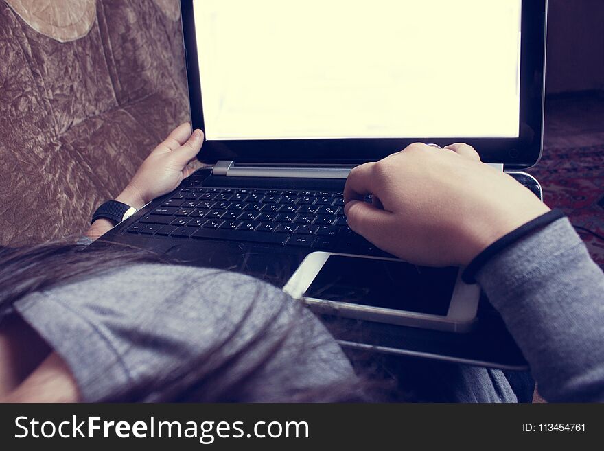 Girl sitting on the couch and working with laptop ..