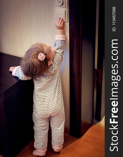 Young cute toddler girl standing at the wall and touching the switch at home. Young cute toddler girl standing at the wall and touching the switch at home.