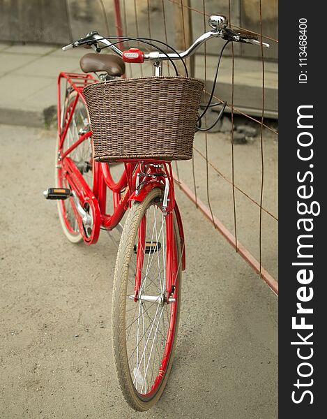 Red vintage city bicycle with brown basket on the handlebar standing outdoors. Red vintage city bicycle with brown basket on the handlebar standing outdoors